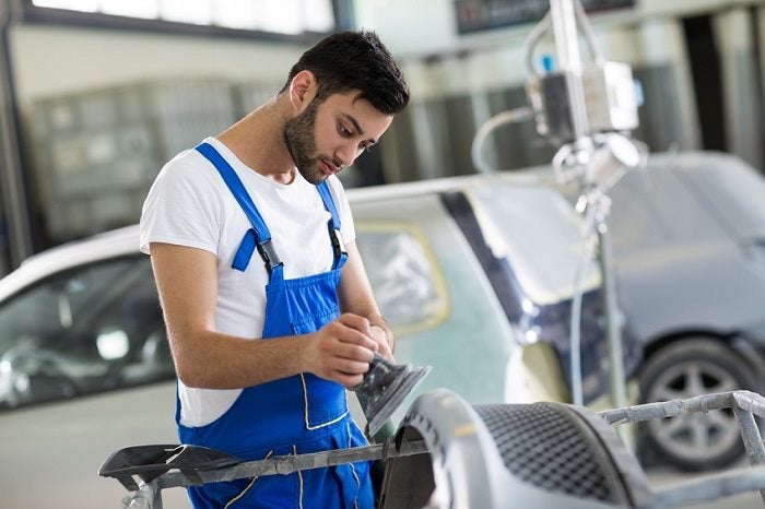 Auto mechanic doing basic inspection in a garage.